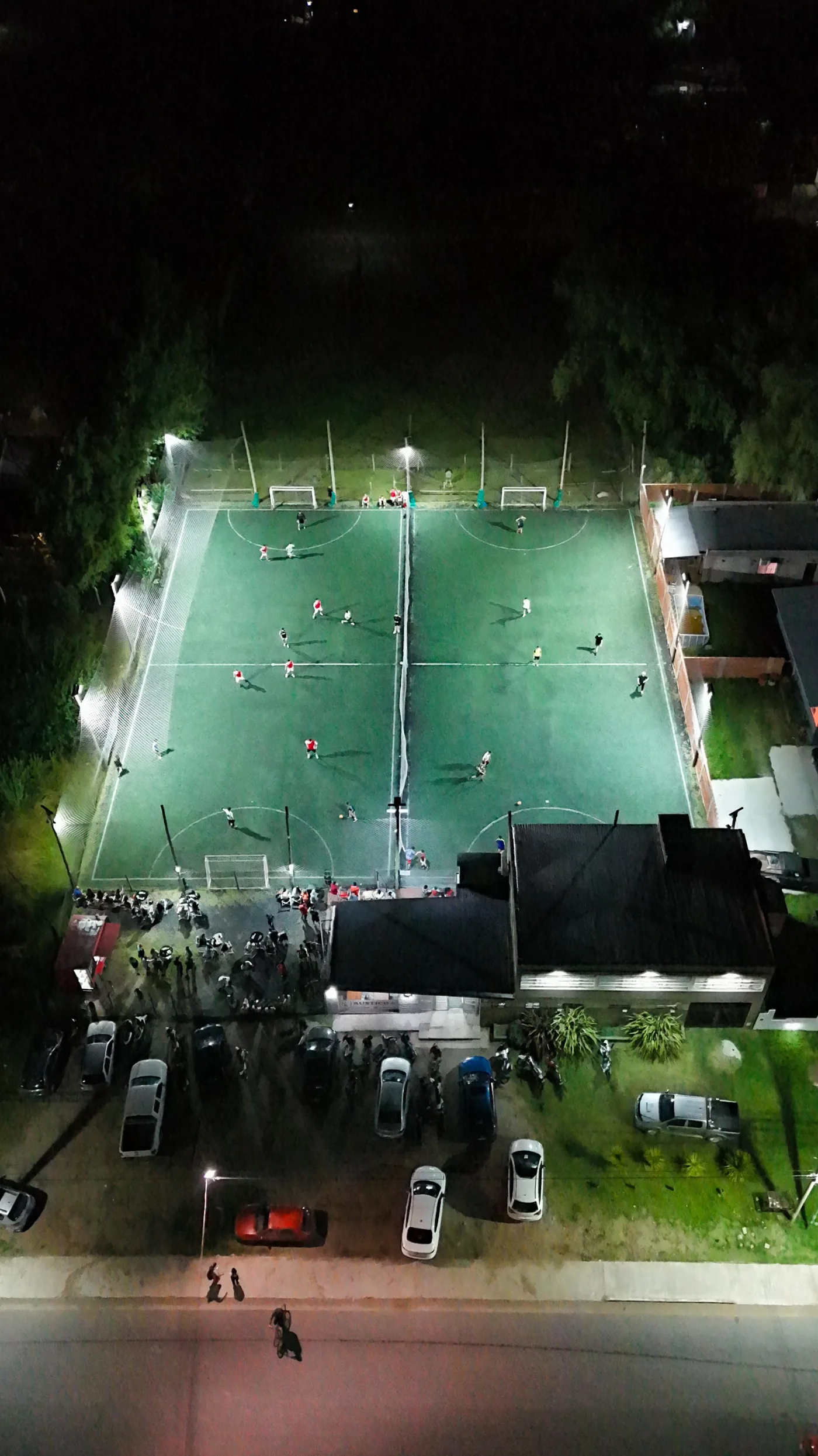 Vista aérea nocturna de una cancha iluminada de Rústico 6